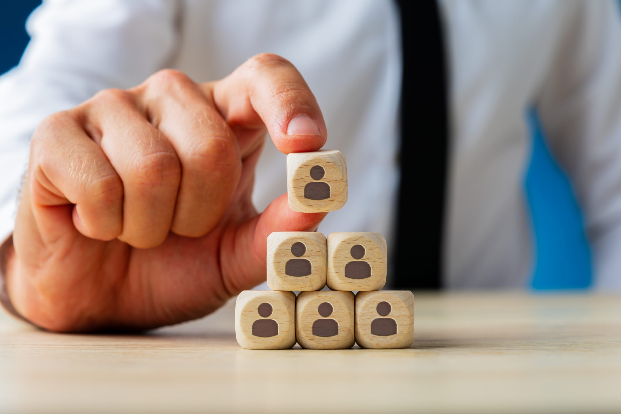 Business executive stacking wooden dices  with people icons on t